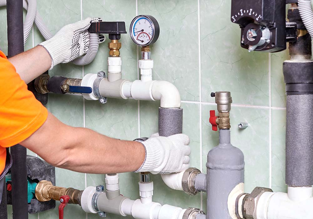 A worker or an engineer checks the operation of the heating system in a room with engineering communications in an apartment building.